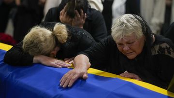 The mother, right, and sister of Army Col. Oleksander Makhachek mourn over the coffin with his remains during a funeral service in Zhytomyr, Ukraine, Friday, June 3, 2022. According to combat comrades Makhachek was killed fighting Russian forces when a shell landed in his position on May 30. (AP Photo/Natacha Pisarenko)