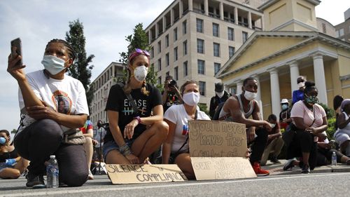 People kneel in silence, Saturday, June 6, 2020, in Washington, in remembrance of George Floyd, who died after being restrained by Minneapolis police officers