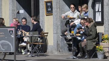 People sit outside in the sun at a cafe bar in central Stockholm, Sweden, on Saturday.