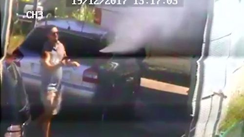 Footage shows a car yard employee spraying water over the fence.