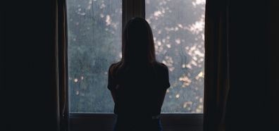 Woman sad standing in front of window
