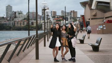 International students Chadanee Shrestha, Swekshya Thapa and Savyata Neupane take selfies during an afternoon walk at the Sydney Opera House.