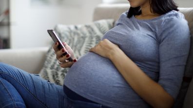 Pregnant woman texting on a mobile phone