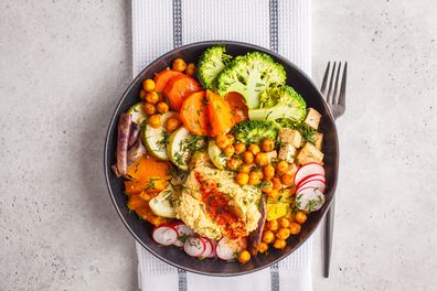 Vegan Buddha bowl with baked vegetables, chickpeas, hummus and tofu on white background. Detox, Clean eating concept.