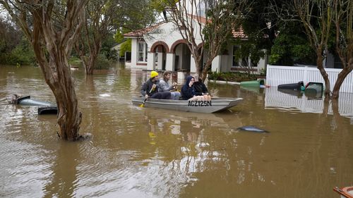 People paddle through a flooded street at Windsor on the outskirts of Sydney.