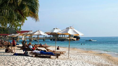 Tourists sunbake on deck chairs in Malaysia. (Image: AAP)