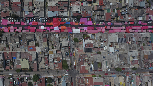 Puestos protegidos del sol con toldos rosas se alinean en una calle durante un mercado callejero semanal reducido pero aún activo en el norte de la Ciudad de México, el domingo 29 de marzo de 2020, mientras muchas personas se quedan en casa en medio de la propagación del nuevo coronavirus. 