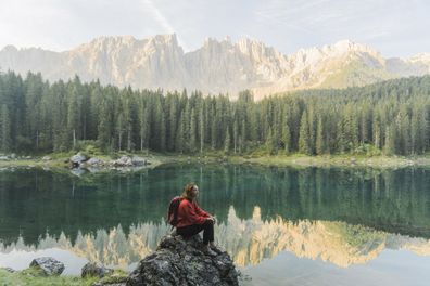 Young Caucasian woman standing and looking at  Lago di Carezza in Dolomites