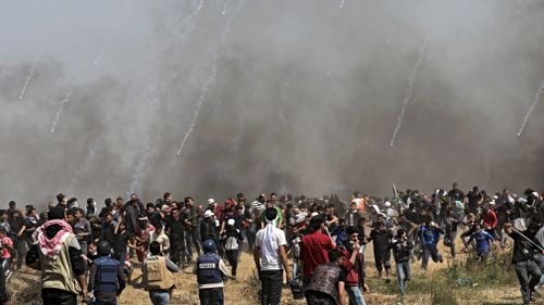 Palestinian protesters take cover from Israeli tear-gas in Gaza City on Friday, April 6, 2018. (AAP)