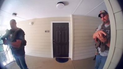 Home security footage of two US Marshals holding their guns up to a door.