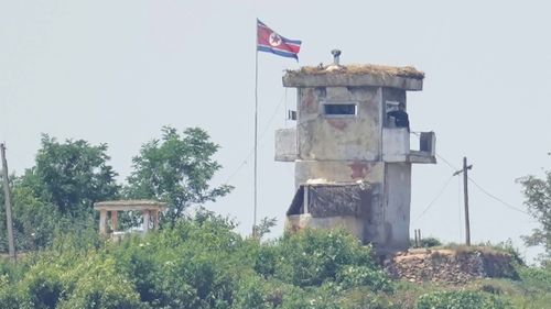 A soldier stands at a North Korean military guard post flying a national flag, seen from Paju, South Korea, in June 2024.