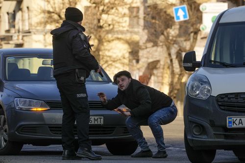 A Ukrainian police officer detains a car driver in a street in Kyiv, Ukraine, Saturday, Feb. 26, 2022.