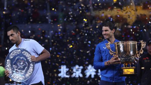 Nick Kyrgios leaves as Rafael Nadal clutches his trophy. (AAP)