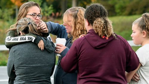 Friends of victims who died in Saturday's fatal limousine crash comfort each other after placing flowers at the intersection.