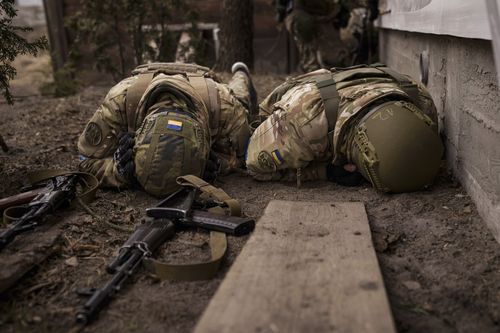 Ukrainian soldiers take cover from incoming artillery fire in Irpin, Ukraine, March 13, 2022 