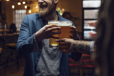 Happy hour at the bar: smiling man bringing beer for his mates.