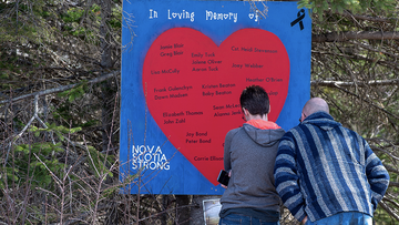 People pay their respects at a roadside memorial in Portapique, Nova Scotia on Sunday, April 26, 2020. A man went on a murder rampage in Portapique and several other Nova Scotia communities killing 22 people. (Andrew Vaughan/The Canadian Press via AP)