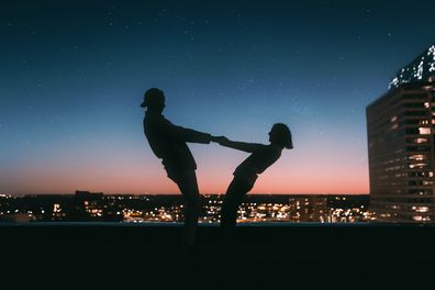 Couple holding hands at sunset on top of city