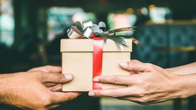 Two people holding Christmas gift