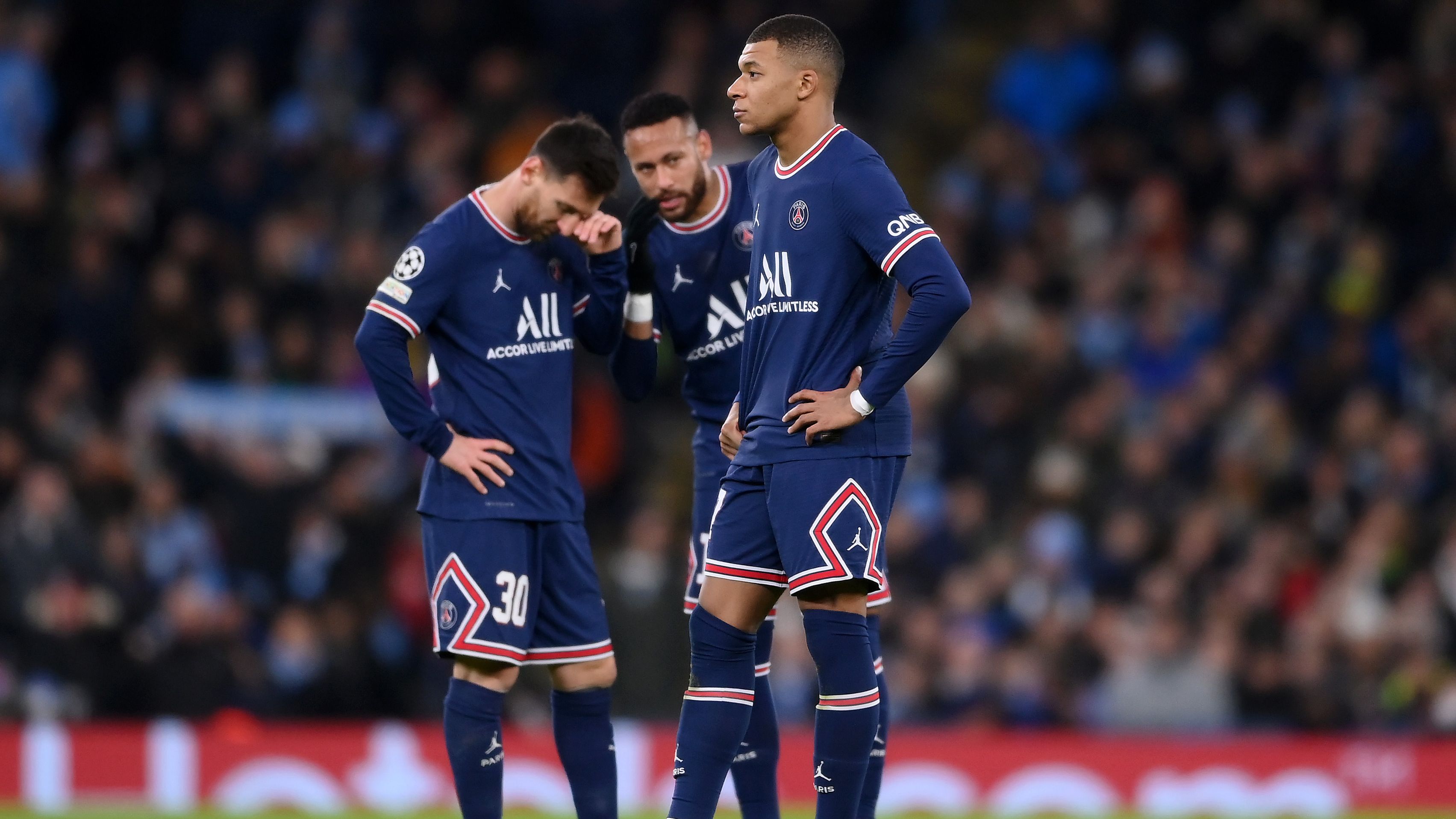 Kylian Mbappe of Paris Saint-Germain looks on as teammates Lionel Messi and Neymar talk in the background.