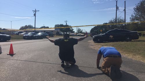 Two community members pray on the edge of the crime scene. (Lizzie Pearl)