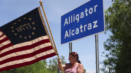 Rana Mourer waves an American flag outside the migrant detention facility dubbed Alligator Alcatraz.