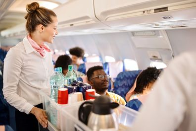Cabin crew pushing service cart and serve to customer on the airplane during flight
