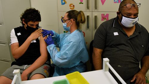 Registered nurse Terissa Angel gives Ty Boney and his father Curtis Boney a COVID-19 vaccine.