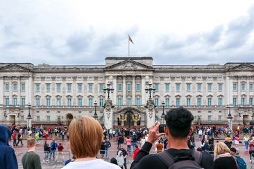 London, UK - 10th October 2023: Tourist taking picture of the majestic and iconic Buckingham Palace in London, royal residence of the King and Queen of the United Kingdom, crowd of tourists outside