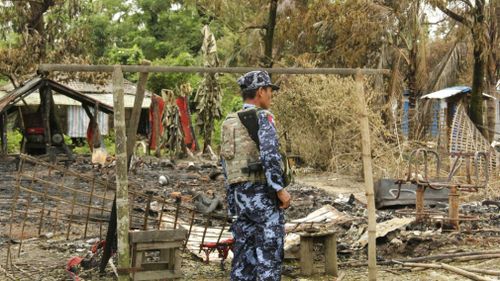 A police officer stands guard around the debris of burnt houses in Ah Lel Than Kyaw village in northern Rakhine state Myanmar . (AAP)