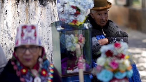 Women stand next to decorated human skulls at the General Cemetery as part of the annual 