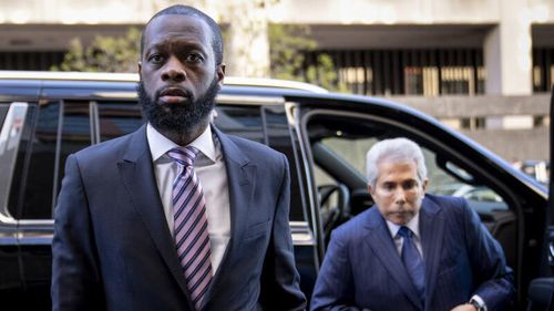 Prakazrel "Pras" Michel, left, a member of the 1990s hip-hop group the Fugees, accompanied by defense lawyer David Kenner, right, arrives at federal court for his trial in an alleged campaign finance conspiracy.