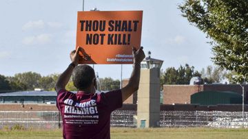 Protester Sylvester Edwards holds a sign up opposing the death penalty from across the street from the federal penitentiary in Terre Haute, Indiana.