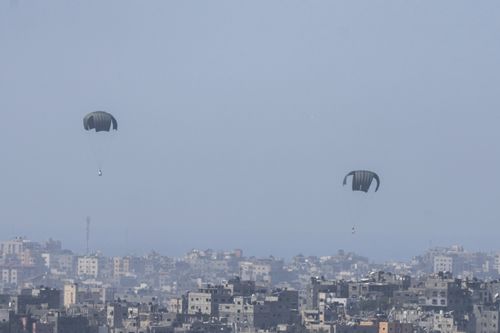 Parachutes drop supplies into the northern Gaza Strip, as seen from southern Israel, Thursday, March 21, 2024 