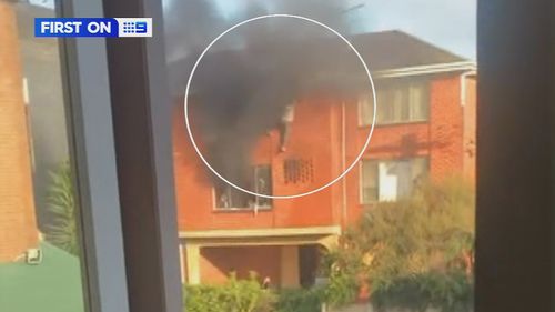 A﻿ man has been saved by his neighbours after they saw him hanging from the window of his burning apartment in Melbourne.