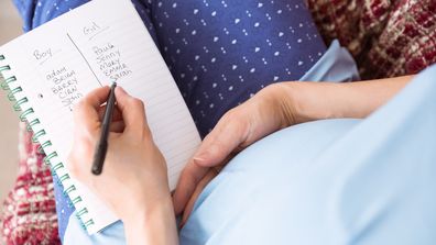 Pregnant woman listing baby names at home in the living room