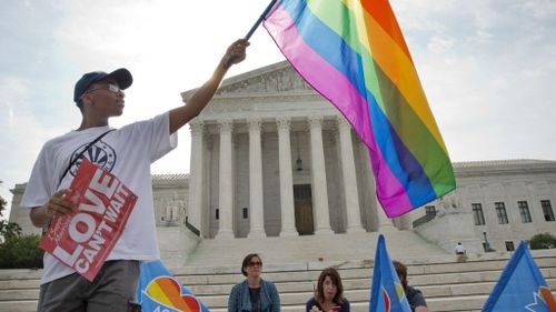 Carlos McKnight, 17, of Washington, holds up a flag in support of gay marriage outside of the Supreme Court in Washington. (AAP)