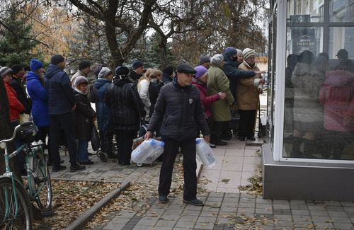 People wait to receive water at a humanitarian aid distribution point in Kramatorsk, Ukraine, Friday, November 11, 2022 