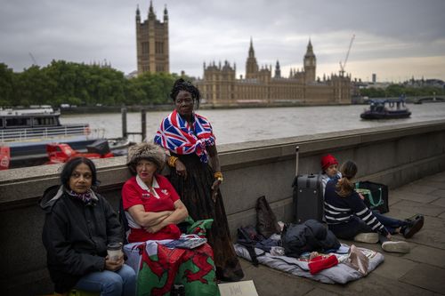 Vanessa, Anne and Grace, from left to right, wait opposite the Palace of Westminster to be first in line bidding farewell to Queen Elizabeth II in London.