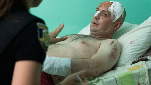 A police officer writes a report as a man wounded by the Russian deadly rocket attack at a shopping centre tells her about the attack in a city hospital in Kremenchuk in Poltava region, Ukraine, Tuesday, June 28, 2022. (AP Photo/Efrem Lukatsky)