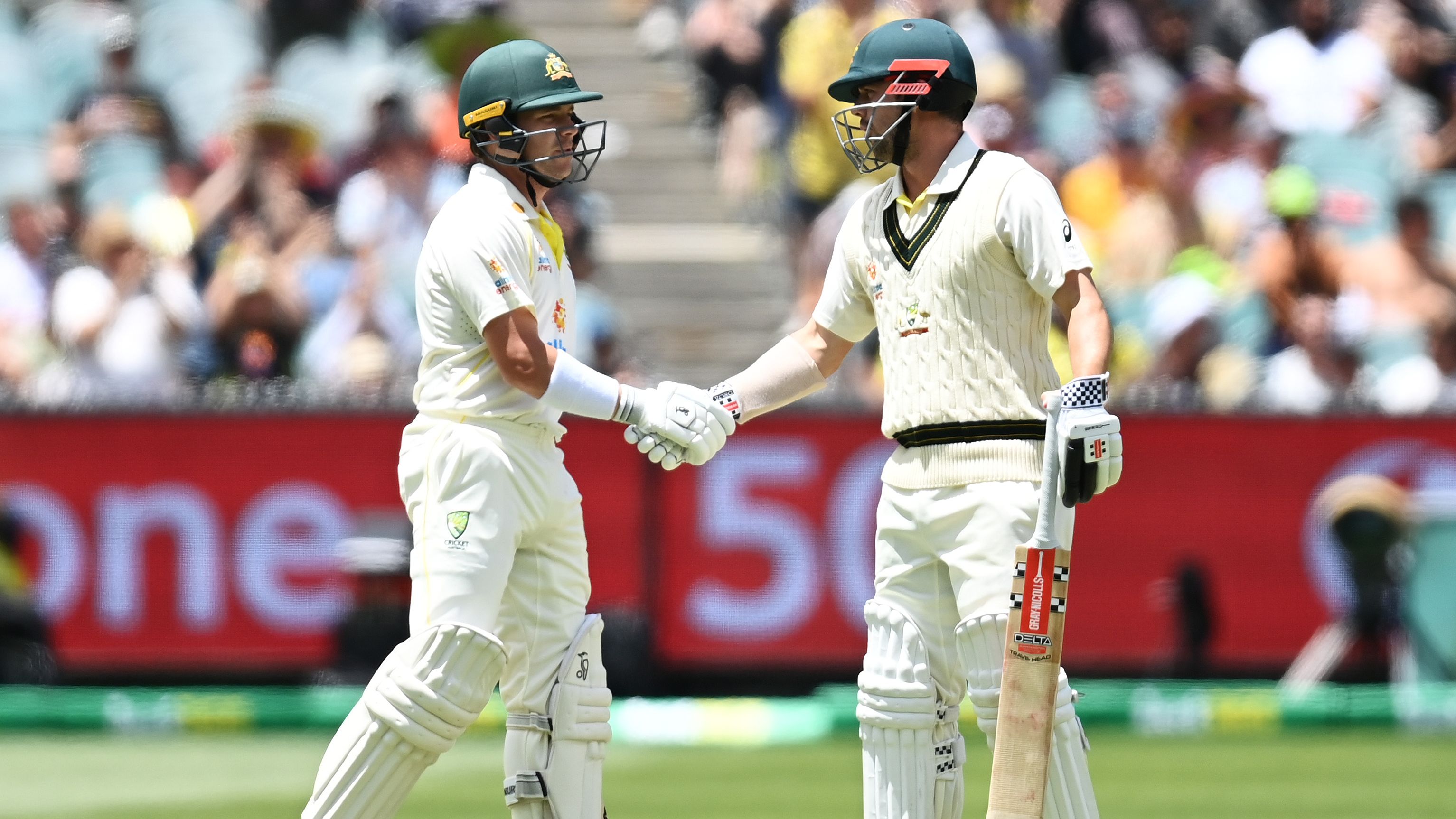 Marcus Harris of Australia is congratulated by teammate Travis Head after scoring a half century during day two of the Ashes Test.