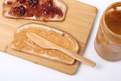 Peanut butter and jam/jelly being spread on bread