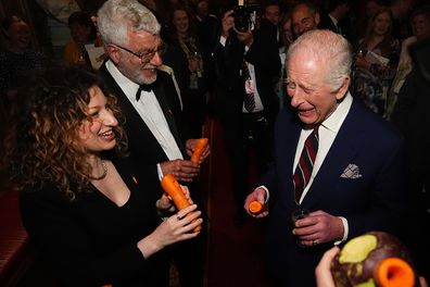 WINDSOR, ENGLAND - APRIL 3: King Charles III plays a carrot with the London Vegetable Orchestra during a reception to recognise those involved in community music across the UK, at Windsor Castle on April 3, 2025 in Windsor, England. The 350 guests include leaders of community music groups and music-related projects, many of whom are volunteers. (Photo by Aaron Chown - WPA Pool/Getty Images)