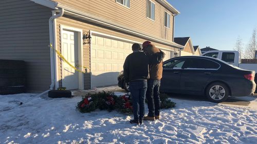 Two friends of seven people whose bodies were found in a Moorhead, Minnesota, home comfort each other next to seven wreaths that were left outside the residence.