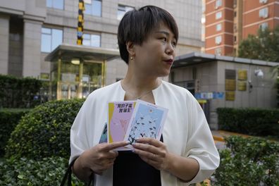 Teresa Xu holds up cards one of which reads "My Womb, My Choice" before attending a court session at the Chaoyang People's Court in Beijing, China, Friday, Sept. 17, 2021. After almost two years, the unmarried woman suing for the right to freeze her eggs in Beijing, is getting her case heard in court in the first legal challenge of its kind in China. (AP Photo/Ng Han Guan)