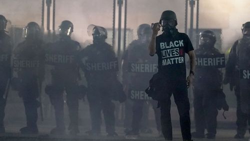 A protester holds up a phone as he stands in front of authorities in Kenosha, Wisconsin.