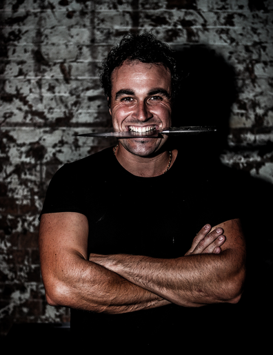 Celebrity chef Miguel Maestre biting onto a knife