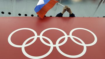 FILE - A Russian flag is held above the Olympic Rings at Adler Arena Skating Center during the Winter Olympics in Sochi, Russia on Feb. 18, 2014. (AP Photo/David J. Phillip, File)