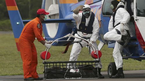 Officers of the National Search and Rescue Agency unload the body of an AirAsia victim. (AAP)