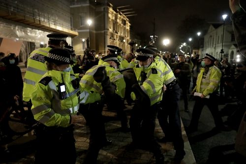 Police officers restrain a man after they were telling people to go home during a march to reflect on the murder of 33 year old marketing executive, Sarah Everard, in London, Monday, March 15, 2021. The British government is under pressure to do more to protect women and ensure the right to protest as Parliament prepares to debate a sweeping crime bill amid anger over the way police broke up a vigil for a young murder victim abducted on the streets of London. (AP Photo/Matt Dunham)